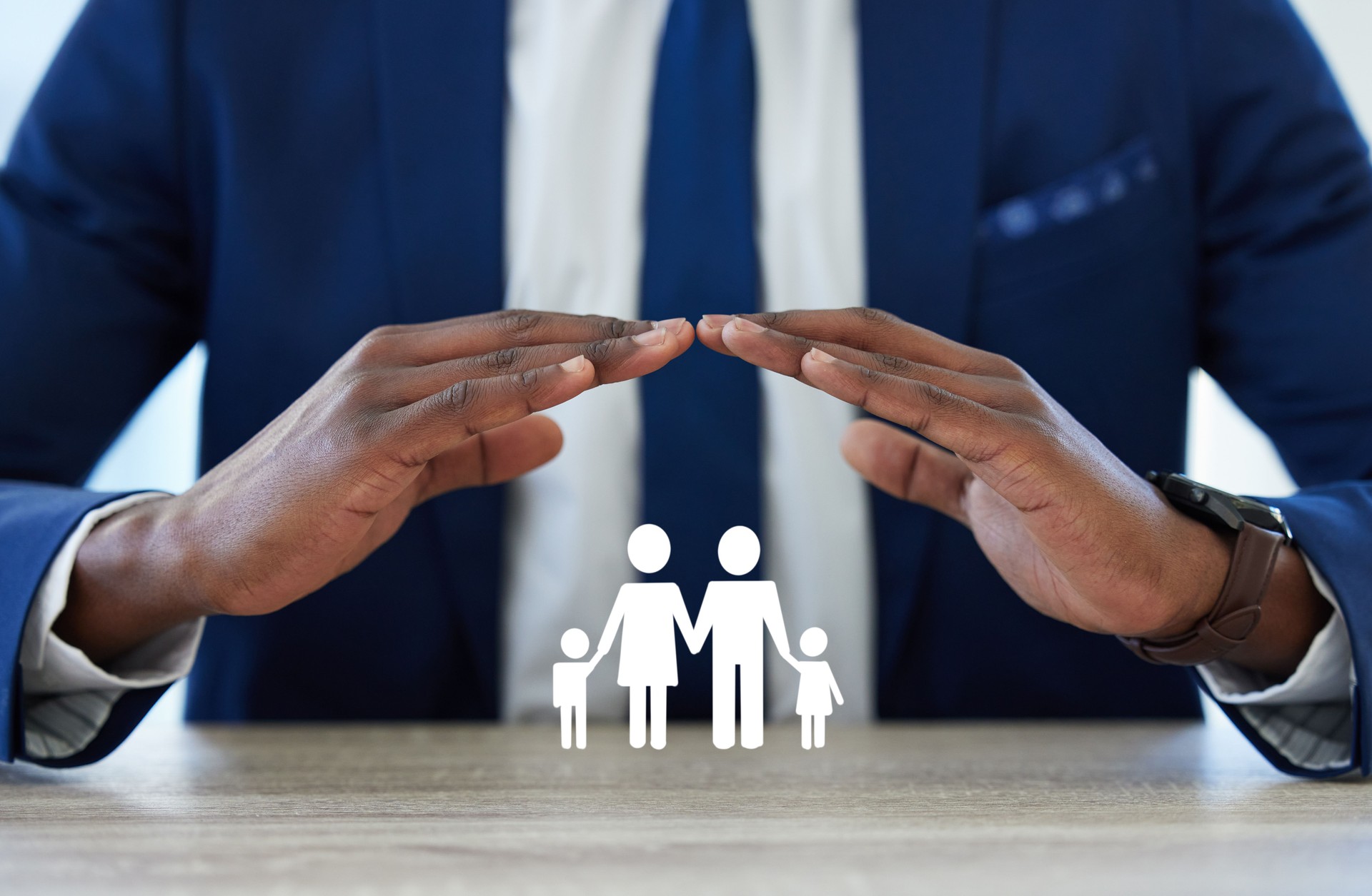 Shot of an unrecognisable businessman’s hands covering a cut out of a family